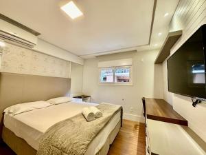 a bedroom with two beds and a flat screen tv at Belíssimo Apto com 3 suítes próximo ao Lago Negro in Gramado