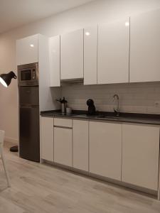 uma cozinha com armários brancos e um frigorífico de aço inoxidável em Gregorio Marañón Apartment 3 em Madri