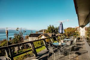 a patio with tables and chairs and an umbrella at Hotel Hosteria Entre Lagos in Puyehue