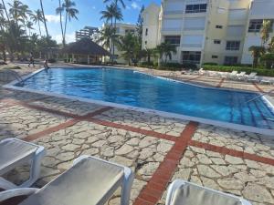 una piscina con 2 sillas y un edificio en Cosy apartamento Juan dolio, en Juan Pedro