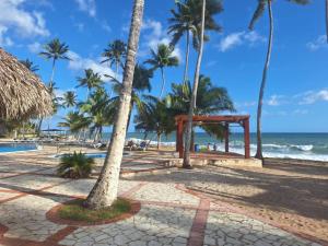 una playa con un pabellón, palmeras y el océano en Cosy apartamento Juan dolio, en Juan Pedro