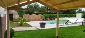 un patio trasero con piscina y pérgola de madera en La Longère de Fréd et Line, en La Garnache