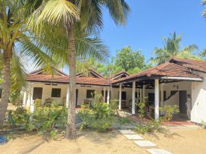una casa con una palmera delante de ella en Harmony Beach Hotel, en Arugam Bay