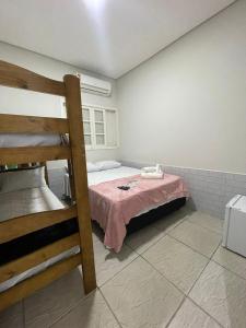 um quarto com uma cama com um cobertor rosa em POUSADA BRISA MAR em Ubatuba