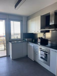 uma cozinha com electrodomésticos brancos e uma grande janela em Diagonal Mar em Barcelona