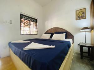 Un dormitorio con una cama azul con toallas. en Harmony Beach Hotel, en Arugam Bay