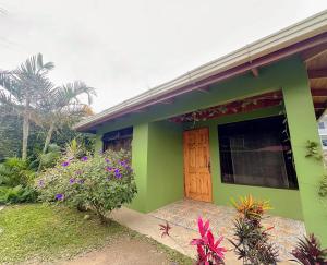 uma casa verde com uma porta de madeira e algumas flores em Edén Guest House em Monteverde