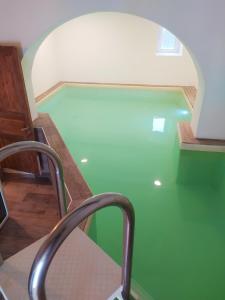a swimming pool with a green floor and a chair at Podere Maletto - Appartamento con PISCINA INTERNA riscaldata Savona in Savona
