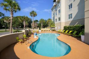 a pool at a hotel with chairs and a building at SpringHill Suites by Marriott Charleston Riverview in Charleston