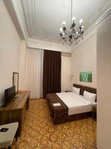 Habitación de hotel con cama y lámpara de araña. en Malakan Boutique Nizami Hotel en Bakú