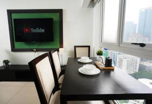 comedor con mesa negra y TV en Home w/ City View - Pool + Fast Wifi 3016, en Manila