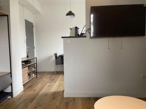 un salon avec une télévision à écran plat sur un mur blanc dans l'établissement Henrigolant, studio cosy, à Toulouse