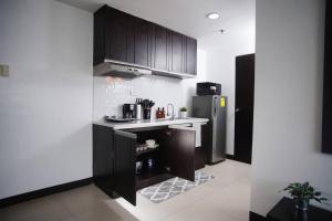 cocina con armarios negros y nevera de acero inoxidable en Home w/ City View - Pool + Fast Wifi 3016, en Manila