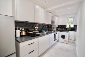 a kitchen with white cabinets and a washer and dryer at Serene 3Bed Escape - Fully Furnished Holiday Haven in Coventry