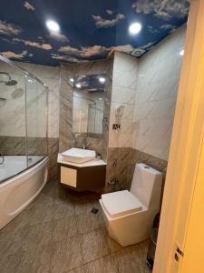 a bathroom with a toilet and a tub and a sink at Malakan Boutique Nizami Hotel in Baku