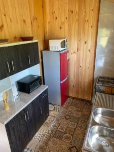 a kitchen with a red refrigerator with a microwave on top at Cabaña laurel lago panguipulli in Cozcoz +9 photos
