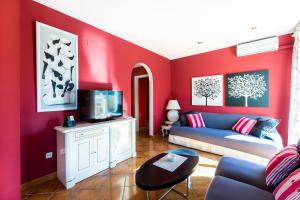 sala de estar con paredes rojas y sofá azul en Fabuloso ROMANI entre mar y montañas, en Bonmont Terres Noves