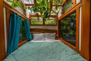 Cama en habitación con 2 ventanas en Tukulolo Treehouses en Makaunga