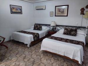 2 Betten in einem Zimmer mit weißen Wänden in der Unterkunft HOTEL PACANDE in Neiva