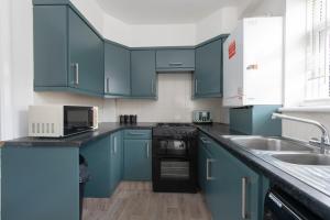 a kitchen with blue cabinets and a sink at 3 Bed House in Rochester 4 beds sleeps 7 in Wainscot