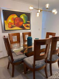 a dining room table with chairs and a painting of fruit at Flor de lirio in Juan López