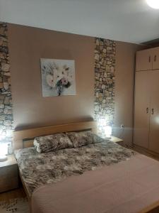 a bedroom with a bed with two lamps and a stone wall at Dvosoban stan u širem centru in Pirot