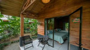a room with a bed and two chairs on a patio at Eden Organic Farm & Bungalows in Fortuna
