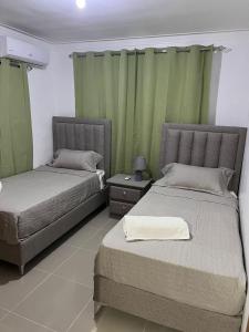 2 camas en una habitación con cortinas verdes en Flor de lirio, en Juan López