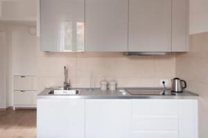 una cucina bianca con armadi bianchi e lavandino di Blanco Apartment - AmbrogioHost a Bologna