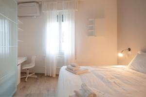 a bedroom with a bed with a desk and a window at Blanco Apartment - AmbrogioHost in Bologna