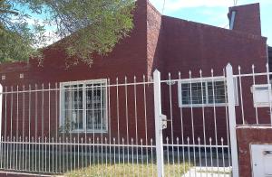a red house with a white fence in front of it at Alojamiento Zen in Puerto Madryn
