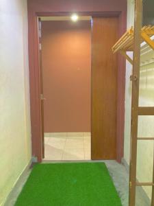 a room with a green carpet in front of a door at NR CYBER ROOMSTAY 2-Shared Apartment in Cyberjaya
