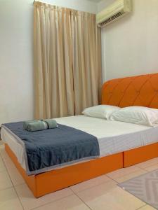 a bedroom with a bed with an orange headboard at NR CYBER ROOMSTAY 2-Shared Apartment in Cyberjaya