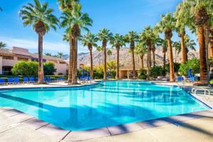 a large swimming pool with palm trees and chairs at Keith Haring Inspired 2BD Deauville Condo - A Ryson Property in Palm Springs