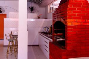 un horno de ladrillo rojo en una cocina con sillas en Pousada Mirante do Sol en Piúma