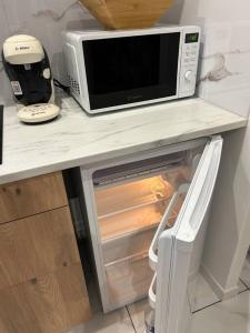a microwave sitting on top of an open refrigerator at Appart cosy proche le havre in Harfleur