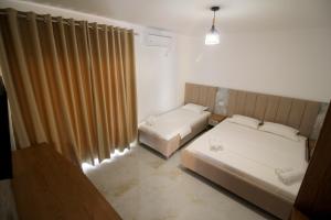 a bedroom with two beds and a window with curtains at Hotel Four Islands in Ksamil