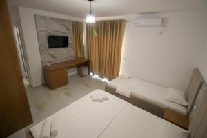 a small white room with a bed and a television at Hotel Four Islands in Ksamil
