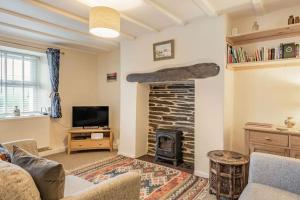 a living room with a stone fireplace and a tv at 5 Tai Nantlle in Nantlle