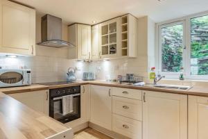 a kitchen with white cabinets and a sink and a stove at 5 Tai Nantlle in Nantlle