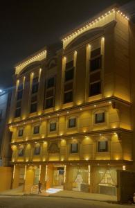 a large yellow building with lights on it at فندق انوار المشاعرالفندقية in Makkah