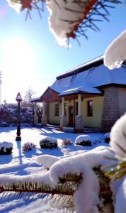 una casa con nieve en el suelo delante de ella en Pensjonat Hagi en Horyniec
