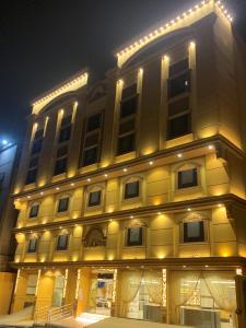 فندق انوار المشاعرالفندقية في مكة المكرمة: مبنى أصفر كبير مع أضواء عليه في الليل