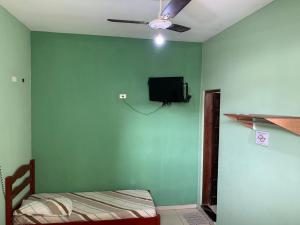 a bedroom with a green wall with a bed and a tv at Hotel Vila de São Vicente in São Vicente
