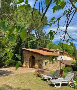 une maison en pierre avec deux chaises longues devant elle dans l'établissement Berenice in Chianti, à Bagno a Ripoli