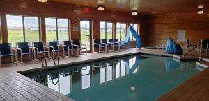- une piscine avec des chaises bleues dans un bâtiment dans l'établissement AmericInn by Wyndham Mauston, à Mauston