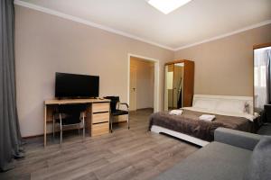 a bedroom with a bed and a desk with a television at На бульваре Мендикулова in Almaty