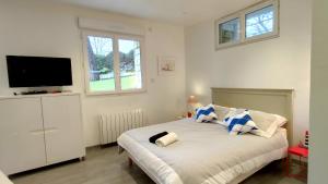 Un dormitorio con una cama con un televisor de pantalla plana. en Les Ecureuils Du Parc à 400 m de la plage, en Royan