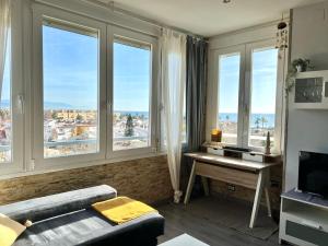 - un salon avec des fenêtres et une table avec un bureau dans l'établissement Espectacular apartamento junto al mar, con piscina en Málaga, à Malaga