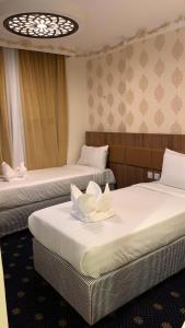 فندق انوار المشاعرالفندقية في مكة المكرمة: غرفة بسريرين عليها زهور بيضاء